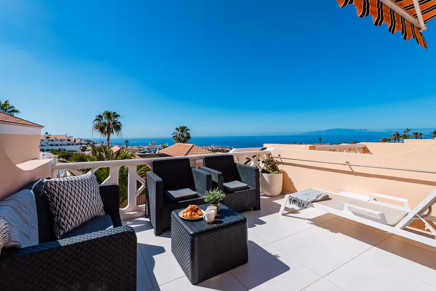 Terrace at Passione Sea Breeze with seating, palms and the sea beyond the rooftops